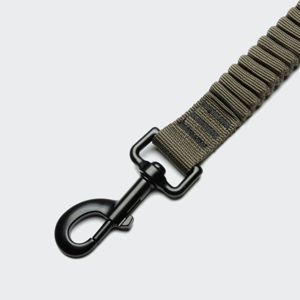 Brown webbing strap with a black metal clip on a light gray background