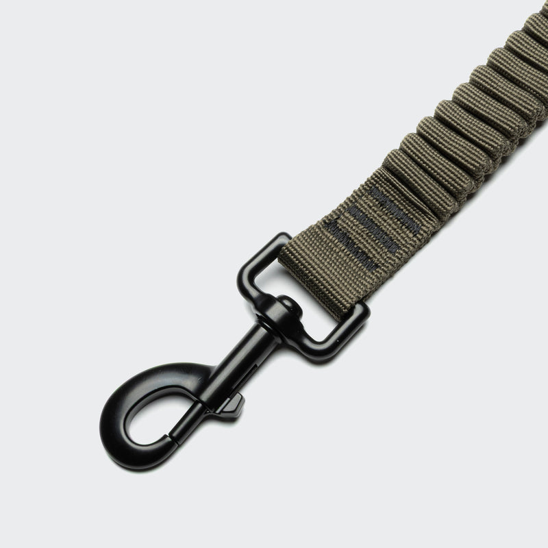 Brown webbing strap with a black metal clip on a light gray background