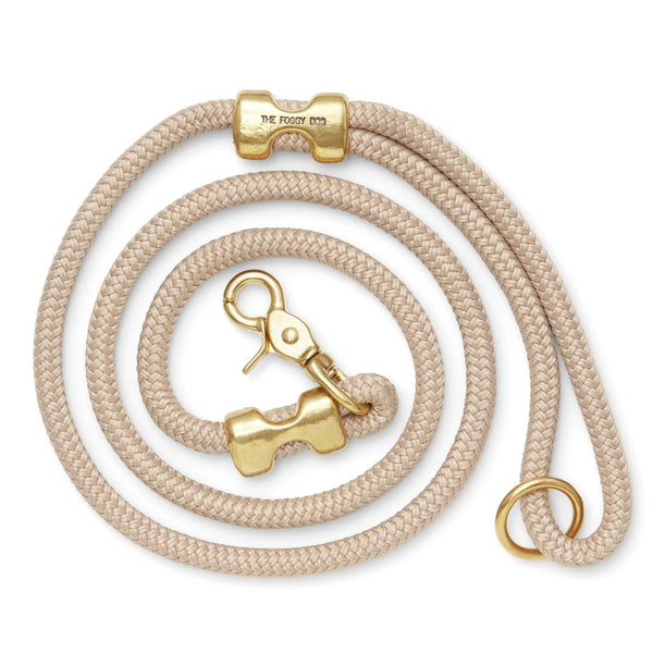 Beige dog leash with gold hardware on a white background