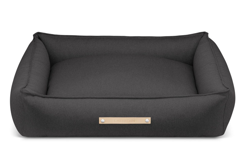 Grey dog bed with a gold label on a white background