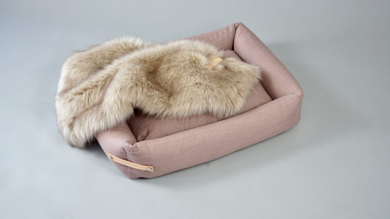 Stokke Pink pet bed with faux fur cover on a light gray background